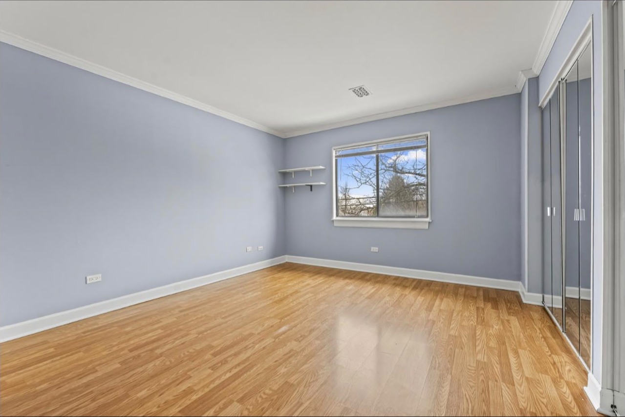 Bedroom painted in soft blue with white coving, skirting and a bright window
