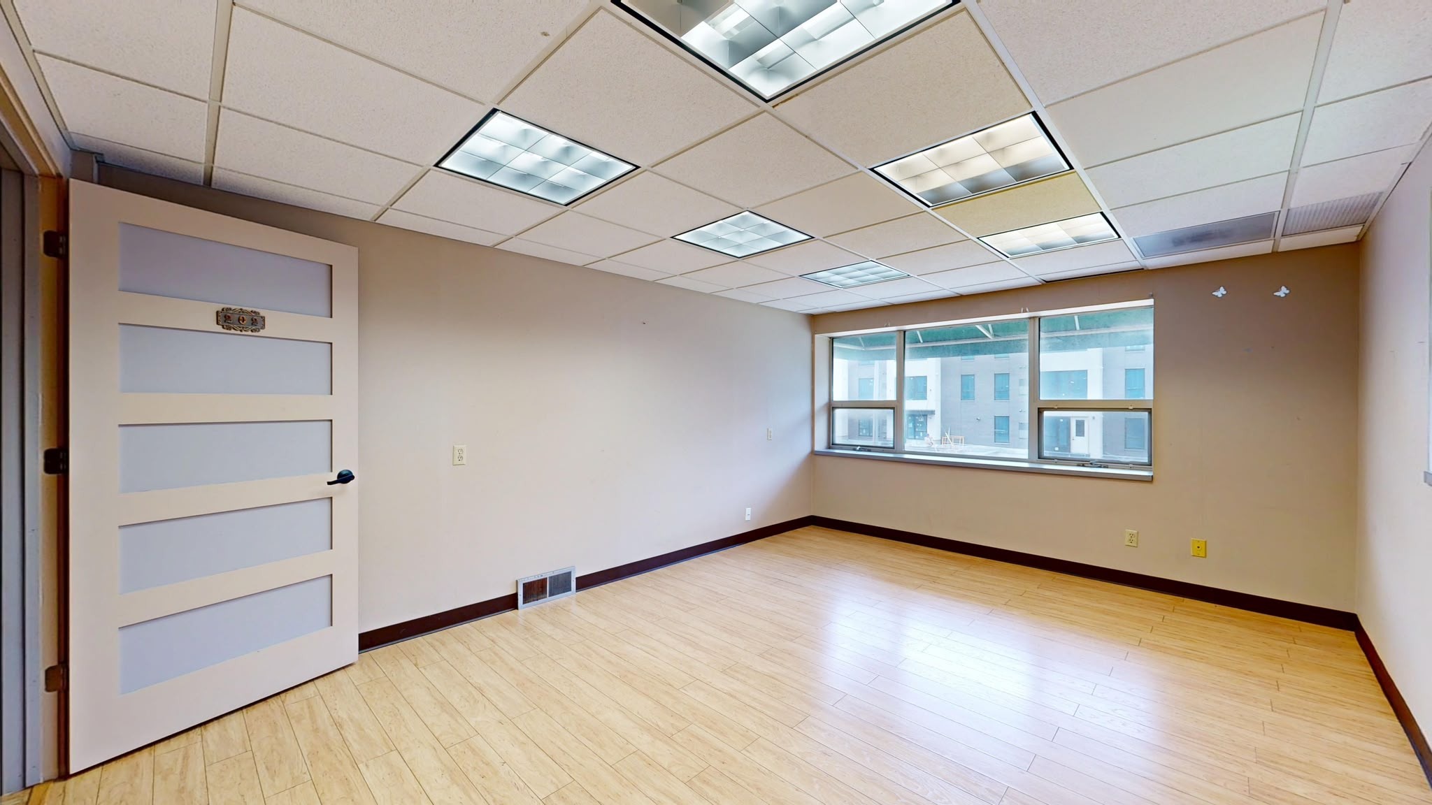 Empty commercial office space with freshly painted walls, suspended ceiling and large windows